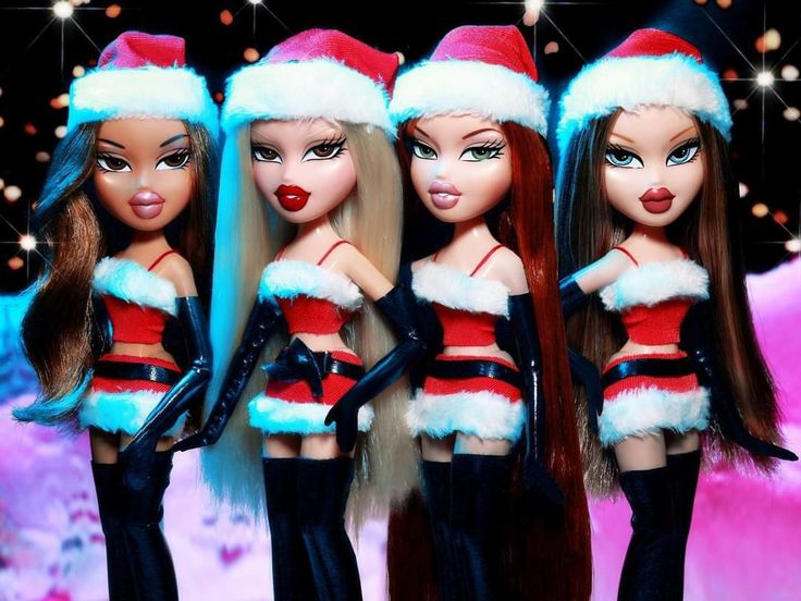 three barbie dolls wearing santa hats and black stockings are standing in front of christmas lights