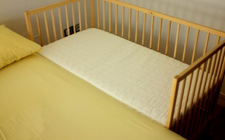 a crib with a mattress and pillows in it