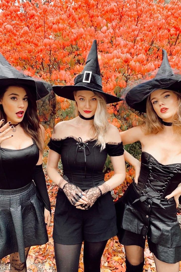 three women dressed up in witch costumes posing for the camera with their hands on their hipss