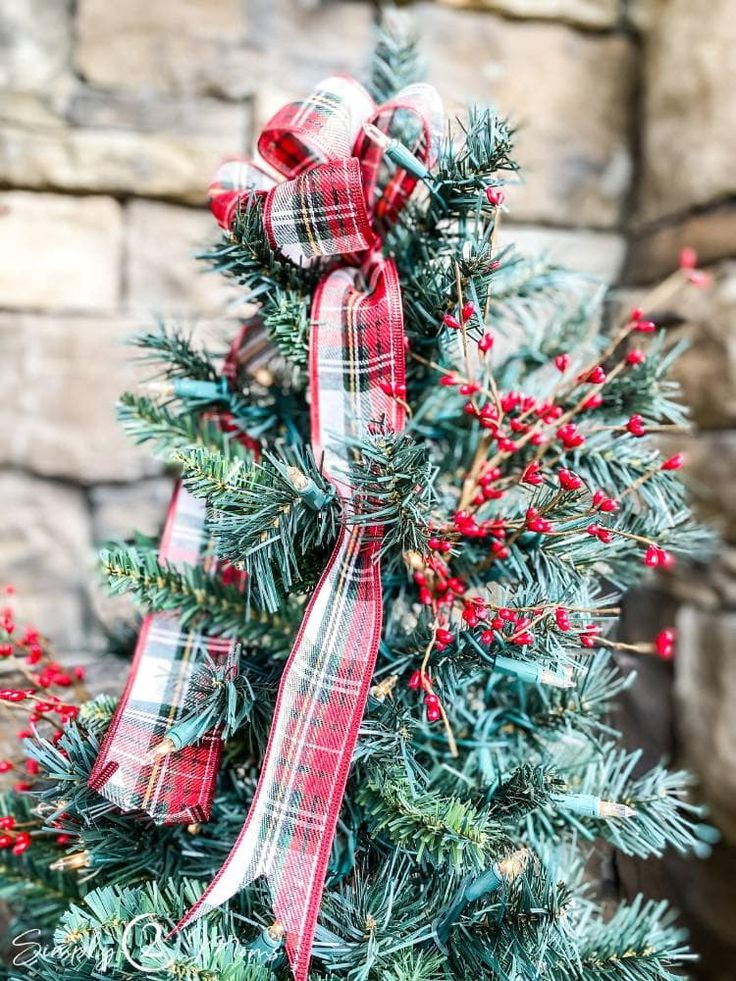 a close up of a christmas tree with red and white bows on it's branches