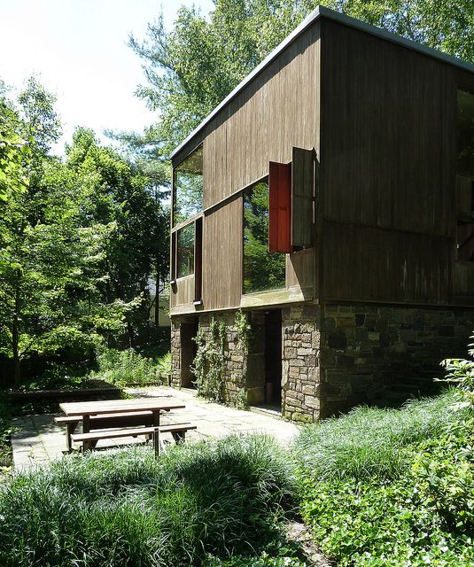 a wooden building sitting on top of a lush green hillside next to a picnic table