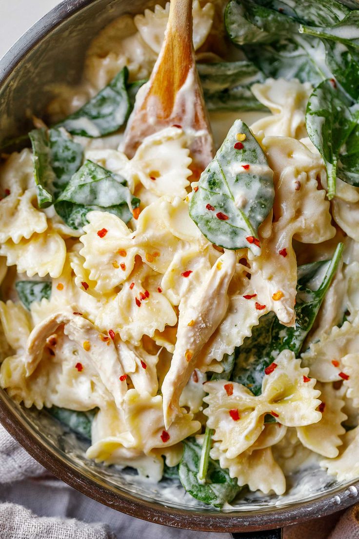 a pan filled with pasta and spinach covered in sauce