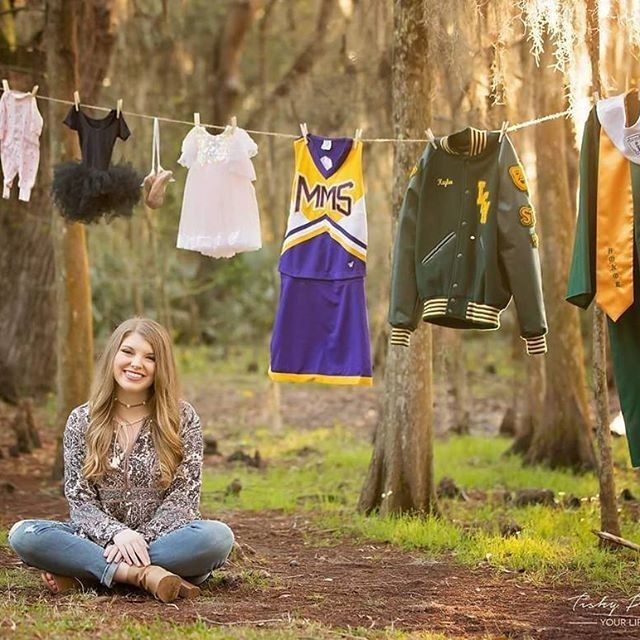 a woman sitting on the ground in front of some clothes hanging from a line over her head