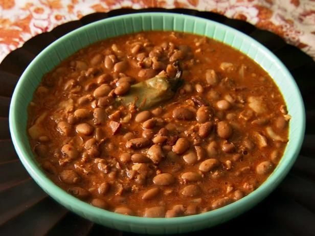 a green bowl filled with beans on top of a table