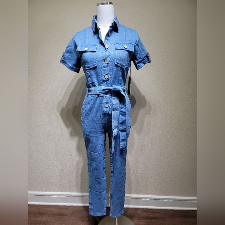 This Denim Jumpsuit Is A Hit. The Self-Tie Adds Such A Classy Touch, With The Bold Buttons Making It Such A Casual Piece. The Stretch Is Great. Put On A Nice Pair Of Sandals Or Sneakers And You're Ready To Hit The Streets. Casual Belted Jeans For Summer, Summer Denim Belted Jeans, Denim Blue Cotton Button-up Jumpsuits And Rompers, Trendy Blue Denim Jumpsuit For Day Out, Blue Casual Button-up Jumpsuits And Rompers, Workwear Denim Jumpsuit With Short Sleeves, Casual Blue Button-up Jumpsuit, Summer Denim Jumpsuit In Medium Wash For Work, Summer Denim Belted Jumpsuits And Rompers