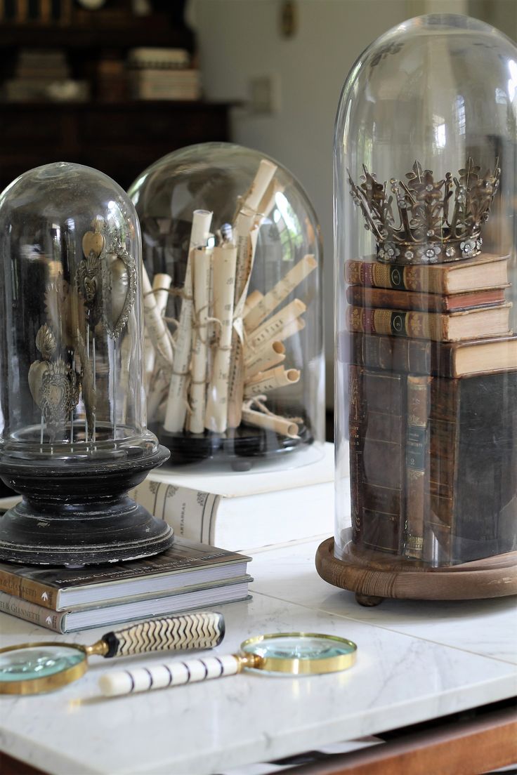 three glass domes sitting on top of a white table next to books and pencils