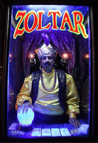 a man sitting in front of a sign that says zoltar