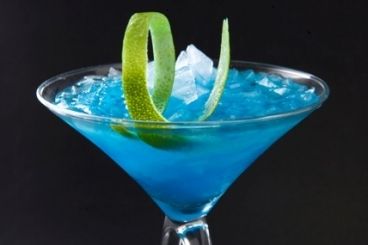 a blue cocktail with lime wedges in it