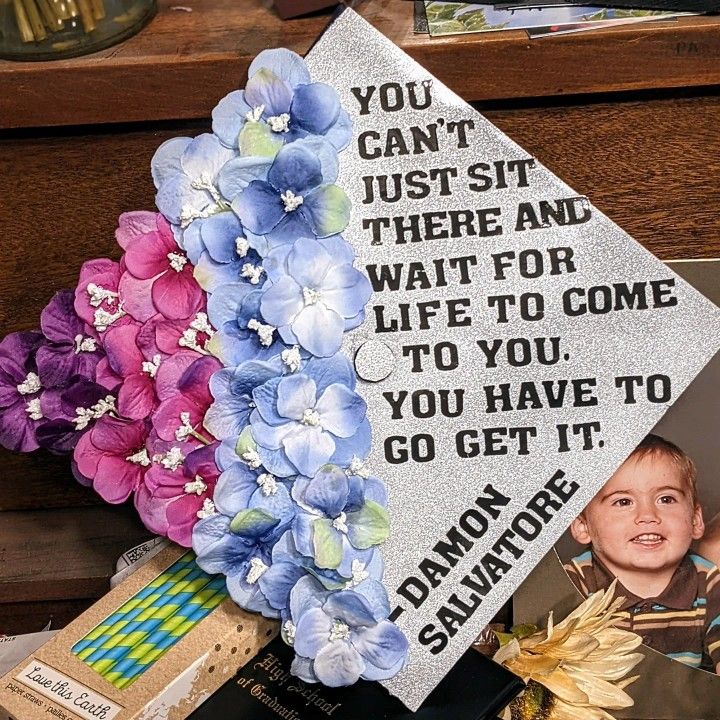 a graduation cap with flowers on it and a card saying you can't just sit there and wait for life to come to you, you have to go get it