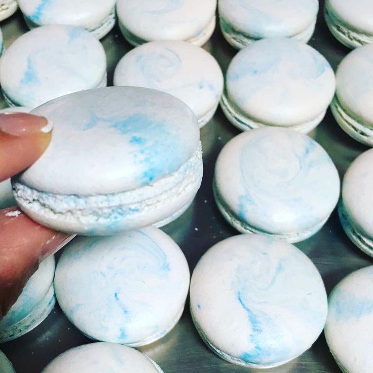 a hand is picking up some blue and white macaroons