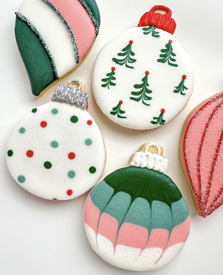 four decorated christmas ornament cookies on a white surface with red, green and blue decorations