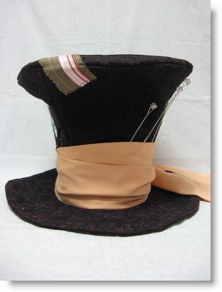 a black top hat with pink ribbon around the brim and silver pins on it