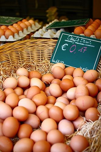 several baskets filled with brown eggs next to each other on display in front of signs