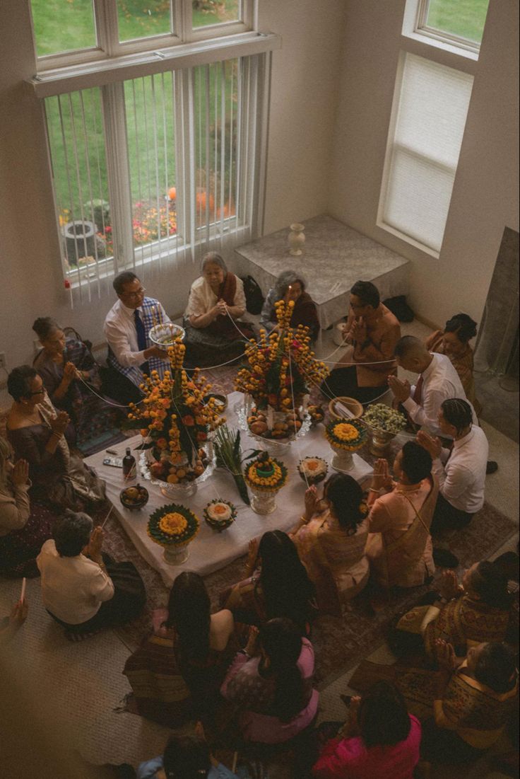 a group of people sitting around a table with food and flowers in front of them