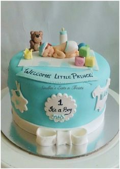 a blue baby shower cake with teddy bears and other items on it's top