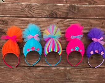 five different colored hats with bows are lined up on a wooden surface and one is wearing a bow