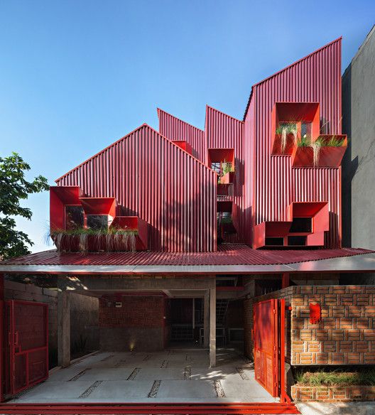 the red building has many windows and plants on it's roof, as well as several planters