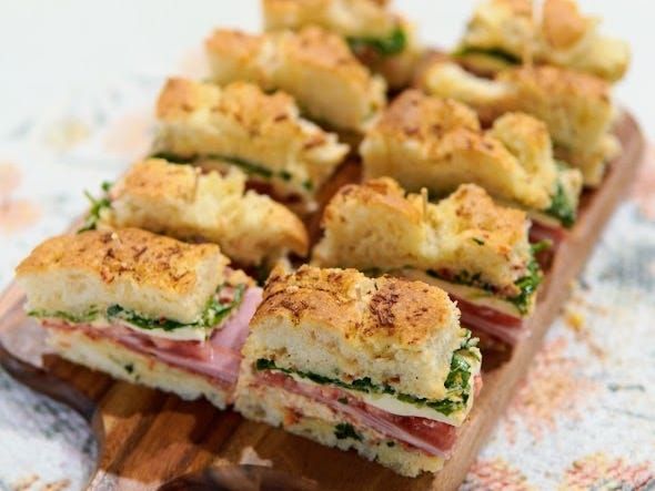 several sandwiches are arranged on a cutting board with bread crumbs and garnishes