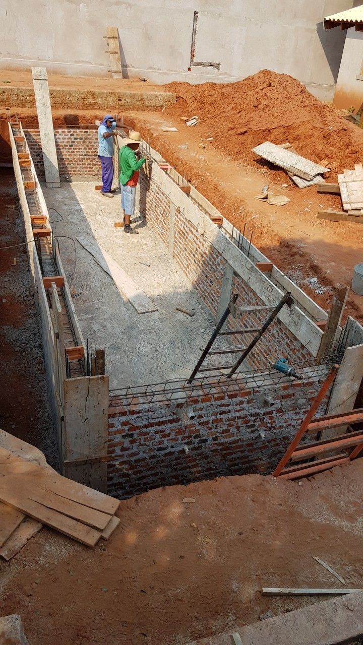 two men are standing on the side of a building under construction