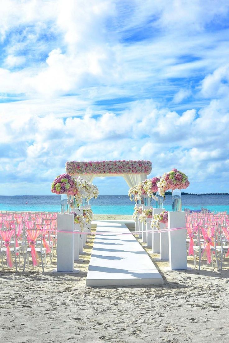 an outdoor ceremony set up on the beach with pink and white flowers in vases