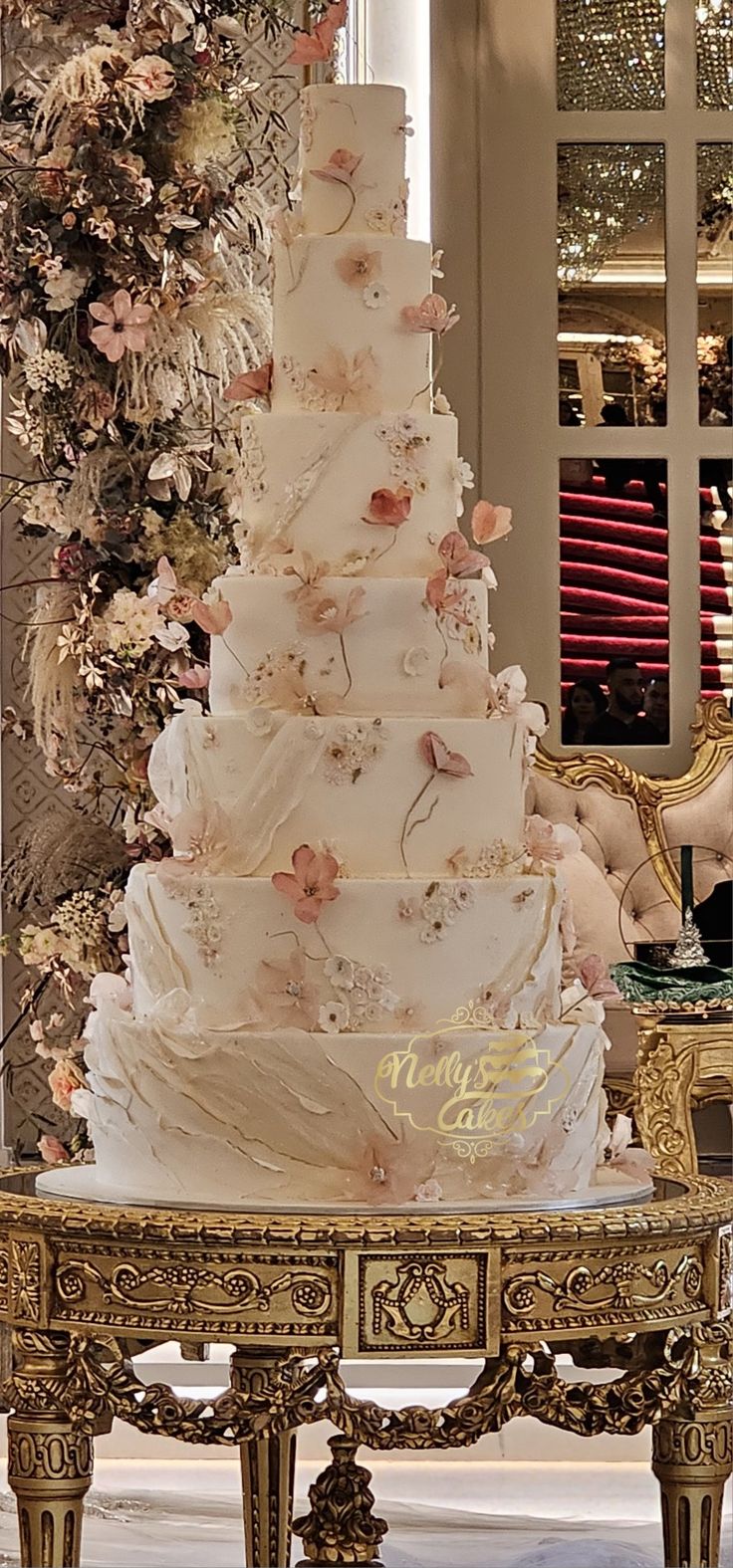 a large white wedding cake sitting on top of a gold table in front of a christmas tree