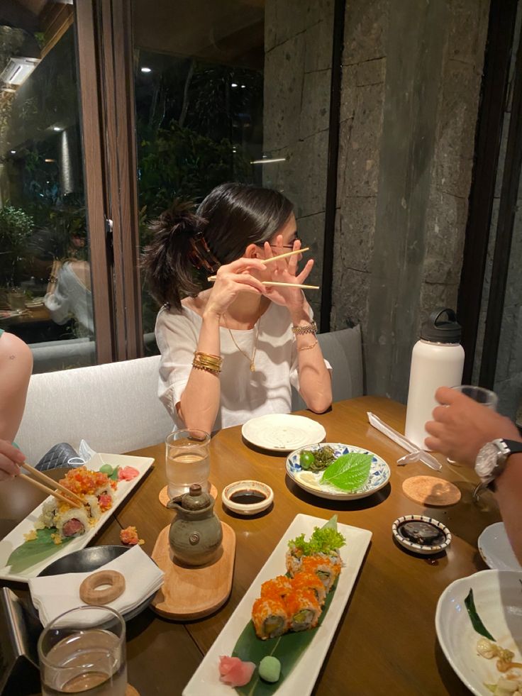 three people sitting at a table eating sushi