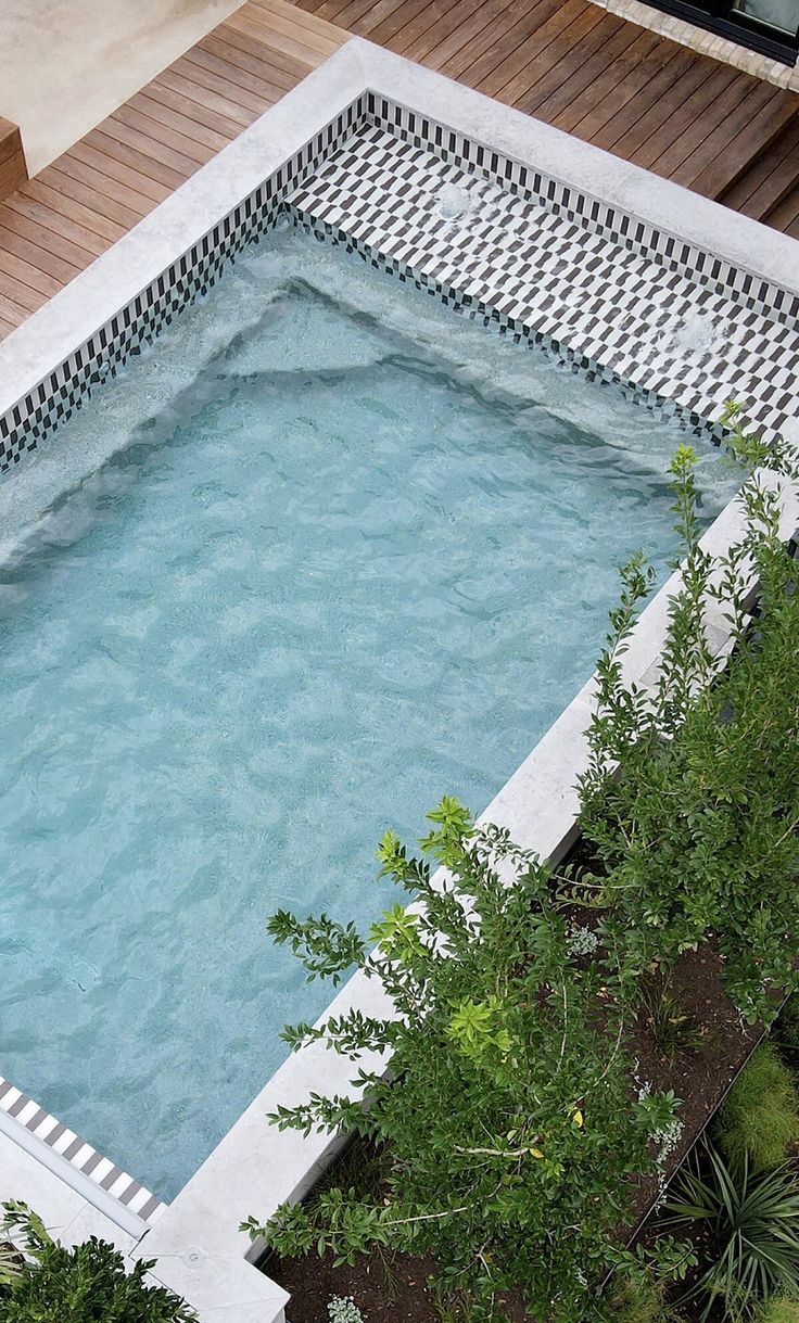 an empty swimming pool surrounded by greenery and wooden decking on top of a building