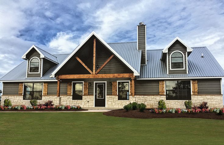 a large house with a metal roof and two windows on the top floor, surrounded by green grass