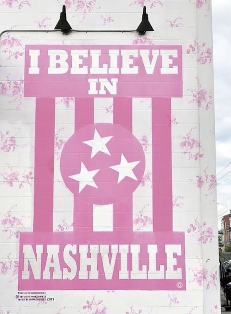 a pink and white sign on the side of a building that says i believe in nashville