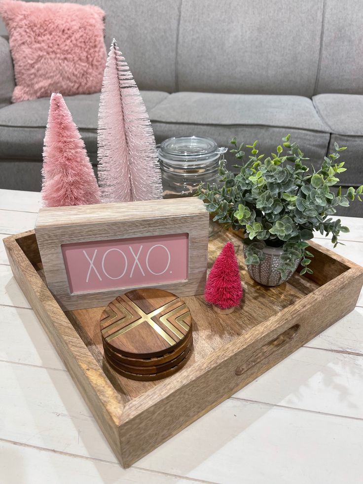 a wooden tray with some plants and other decorations on top of it, sitting on a white table