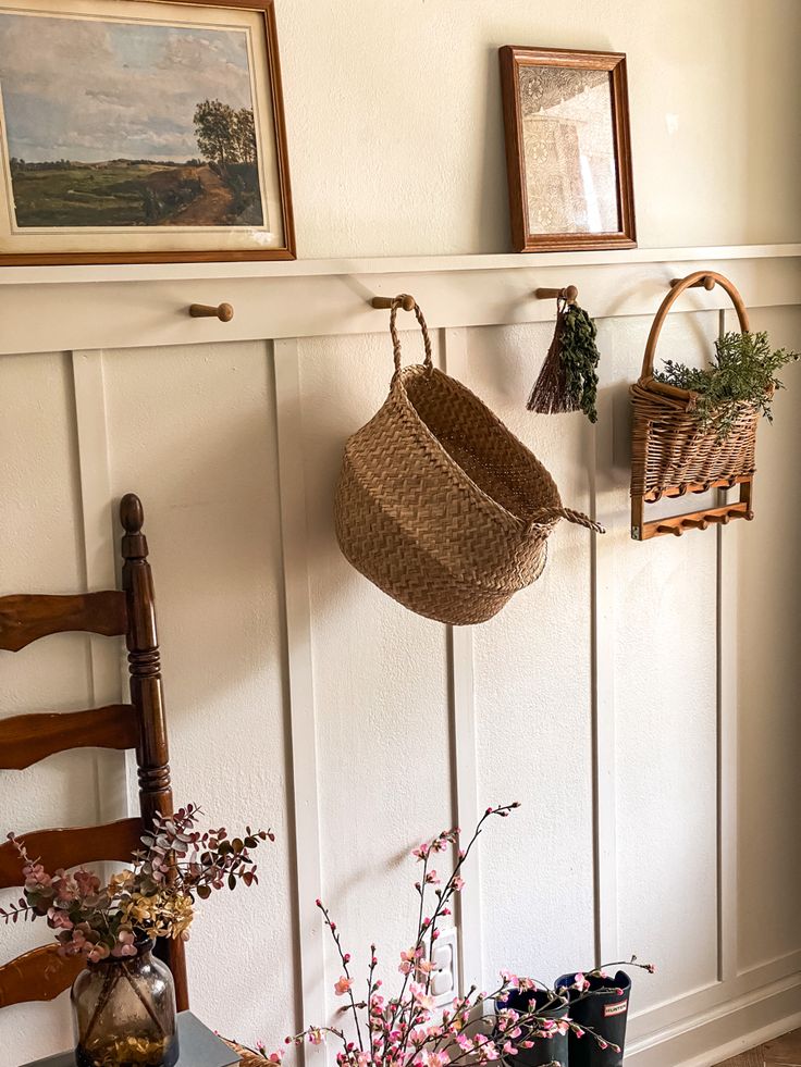 a basket hanging from the side of a wall next to some flowers and other items