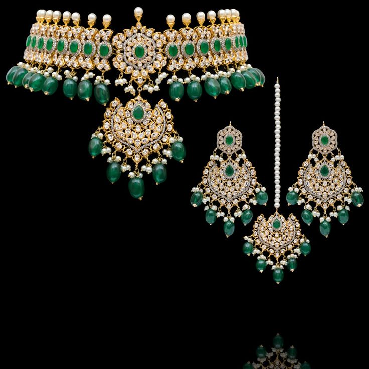 Indulge in the allure of this exquisite jewelry set and let contemporary grace redefine your fashion narrative! Radiate elegance and dangle in delight with our enchanting Esha Set – a mesmerizing blend of elegance and vibrancy meticulously crafted with sparkling zircons, complemented by the refreshing allure of emerald green stones, and embellished with delicately dangling green beads to elevate your style with the perfect harmony of sophistication and playfulness. The set includes a necklace, a maang teekah and a pair of trendy earrings. Approximate earrings length is 3.25". Gold-plated on high-quality brass as base metal. Made by order. Kindly allow 4-6 weeks for the delivery of this item. For custom or urgent requests, please contact support@alacouture.com. *Please Note: We use faux sto Hand Set Jewelry Sets For Reception, Luxury Cubic Zirconia Jewelry Sets For Festive Occasion, Elegant Jeweled Jewelry Sets For Reception, Elegant Festive Sets With American Diamond, Elegant Kundan Hand Set, Bollywood Style Diamond Jewelry With Stone Work, Formal Cubic Zirconia Chandbali Jewelry, Luxury Diamond Jewelry Sets For Festive Season, Elegant Bridal Sets With Crystal Stone Work