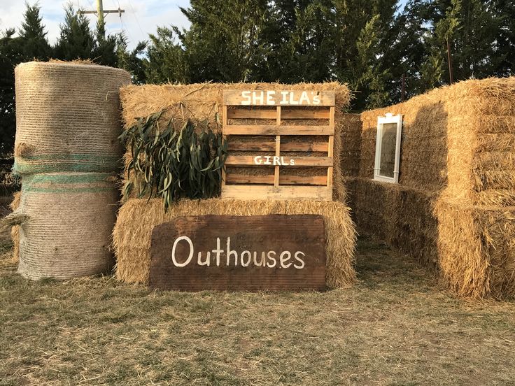 hay bales stacked on top of each other in front of a sign that says outhouse