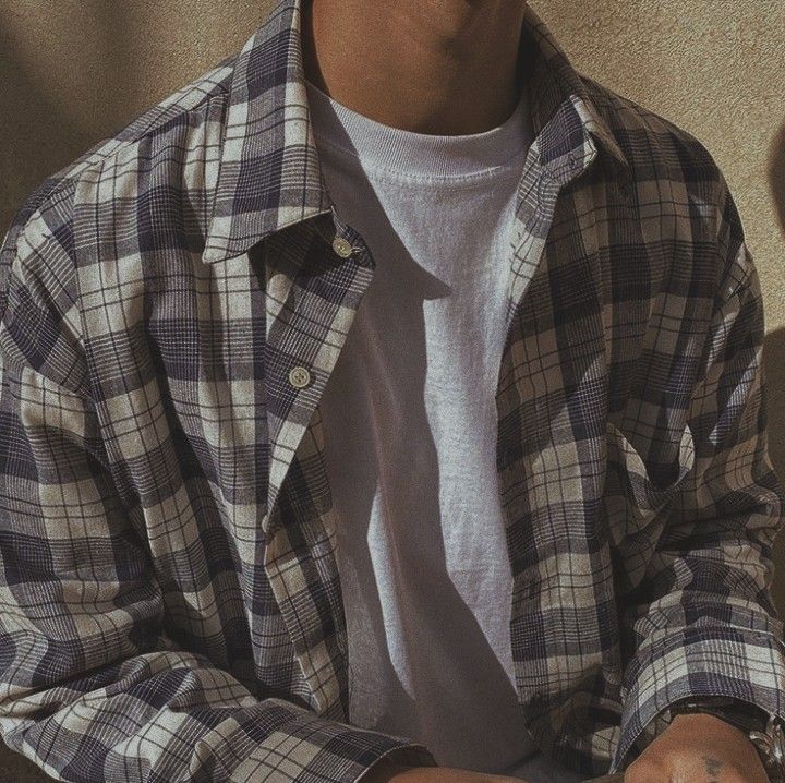 a man sitting down with his hand on his hip and wearing a white t - shirt