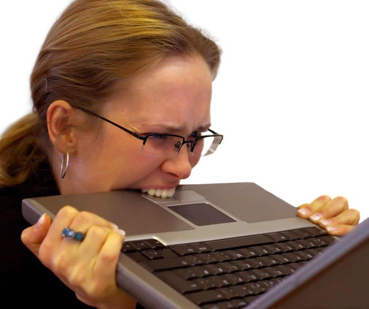 a woman with glasses biting into a laptop keyboard