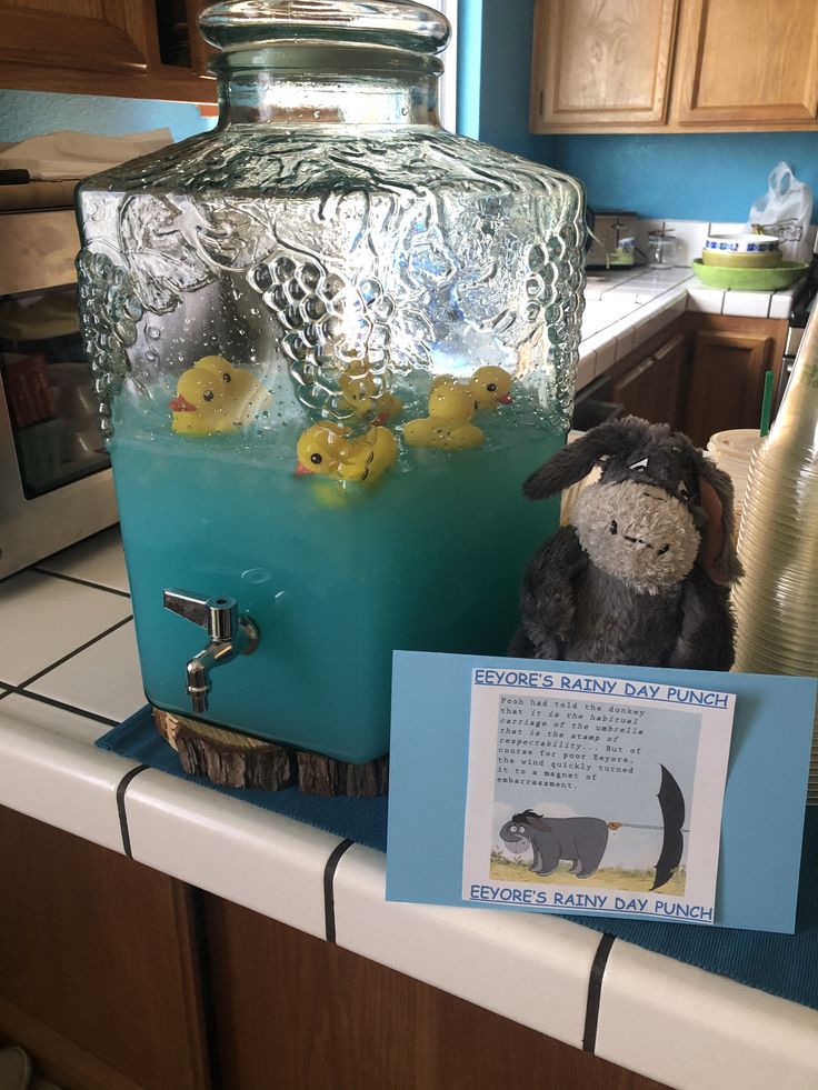 a stuffed animal sitting on top of a counter next to a jar filled with blue liquid