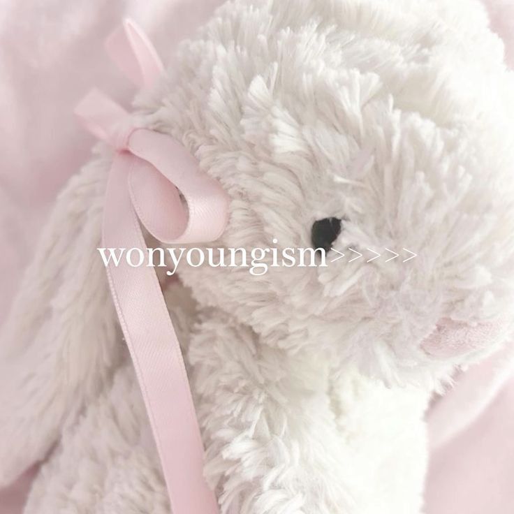 a white stuffed animal with a pink ribbon around its neck