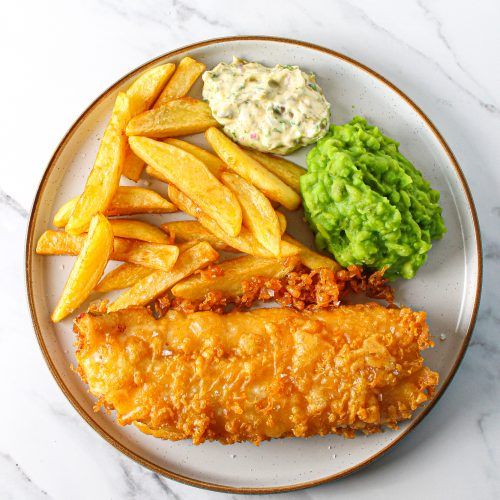 a plate with fish, fries and guacamole on it