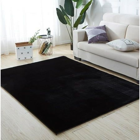 a living room with a white couch and black rug