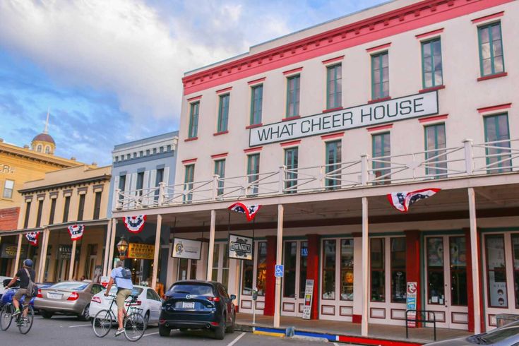 people are riding bikes down the street in front of a building that says what cheer house