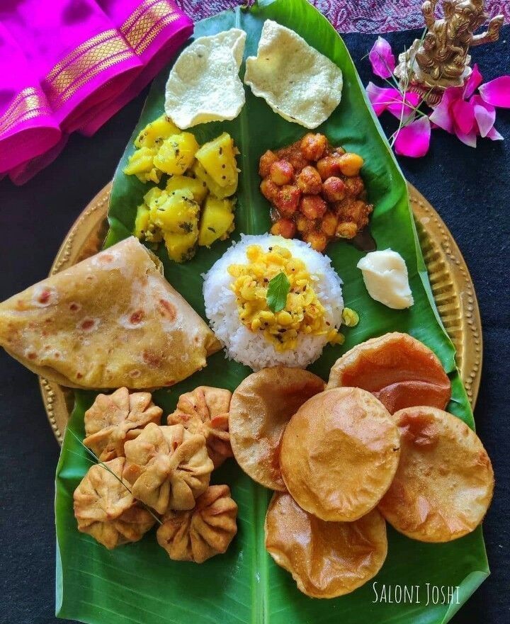 a plate full of different types of food on a banana leaf with flowers in the background