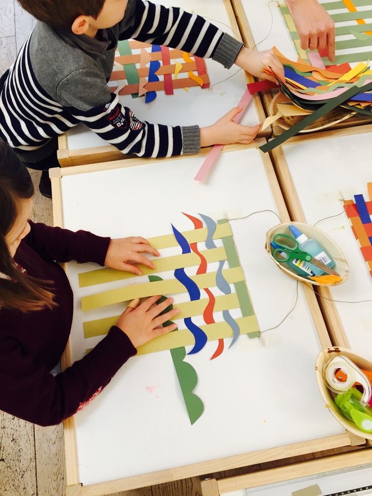 two children are making art with construction paper