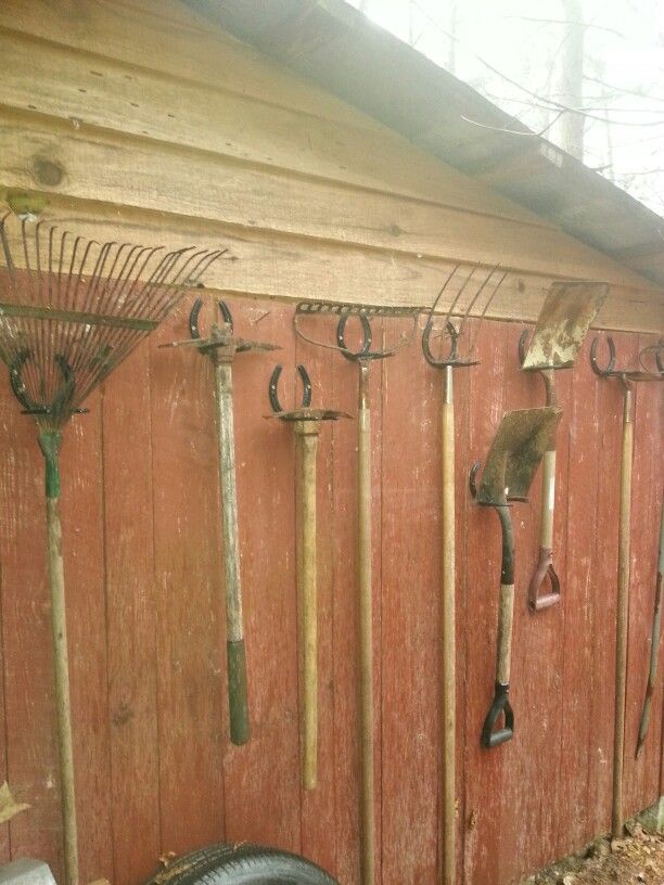 there are many garden tools hanging on the wall