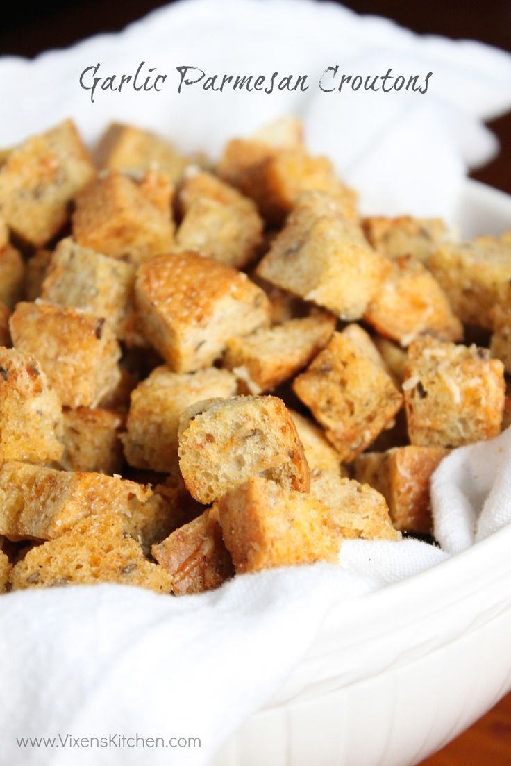 a white bowl filled with croutons sitting on top of a wooden table