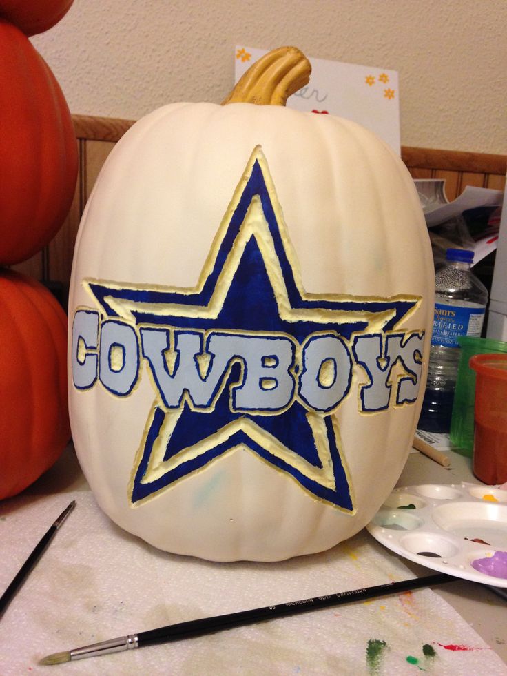 a large white pumpkin with the word cowboys painted on it next to some paintbrushes