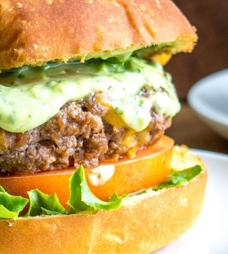 a hamburger with lettuce, tomato and cheese on it sitting on a plate