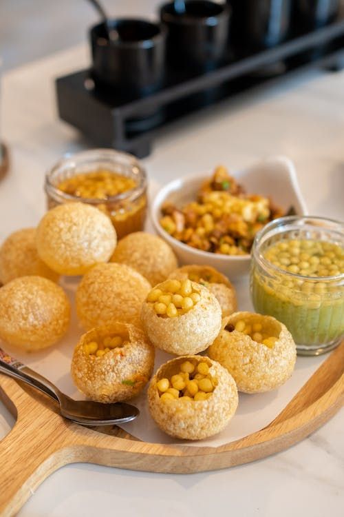 some food is sitting on a wooden platter with spoons and bowls next to it