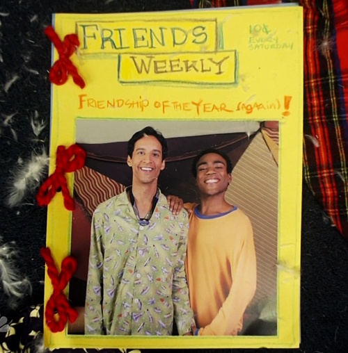 a couple of men standing next to each other in front of a yellow sign that says friends weekly