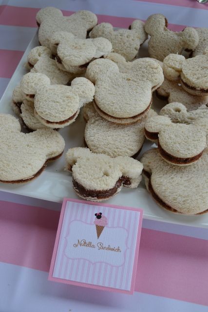 mickey mouse cookies are on a plate with a pink and white table cloth behind them