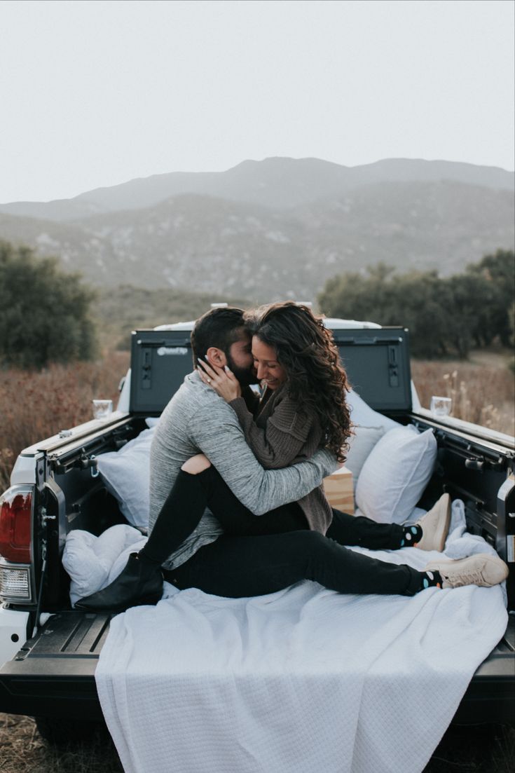 a man and woman hugging in the back of a pick up truck